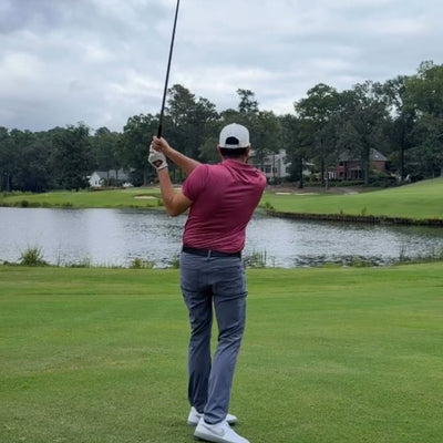 Person playing golf on a green course with a lake in the background